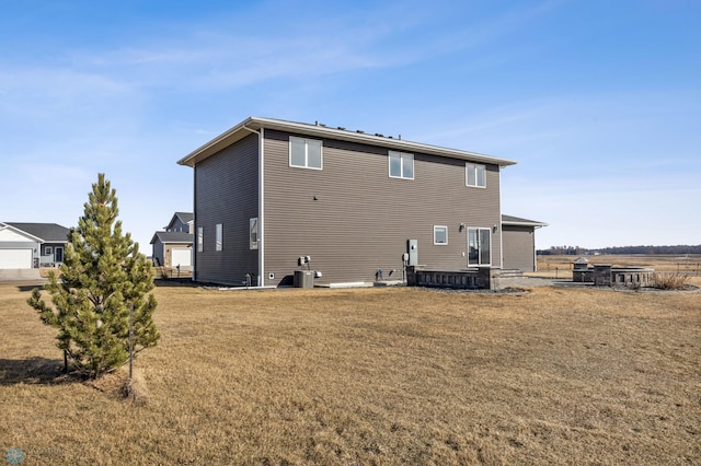 rear view of house with central AC unit and a lawn