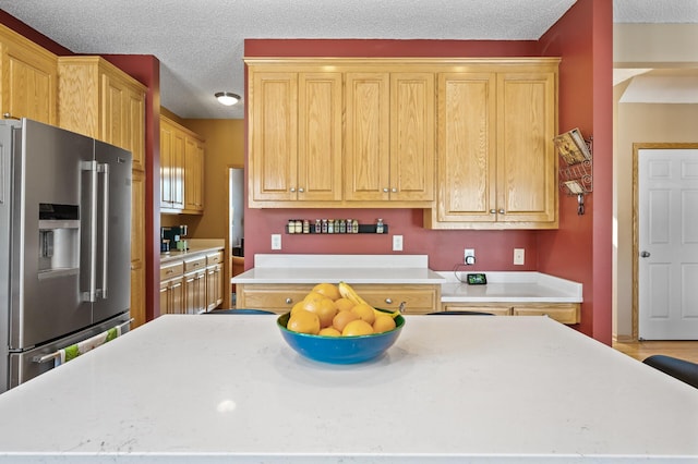 kitchen with light countertops, a textured ceiling, high end refrigerator, and light brown cabinetry