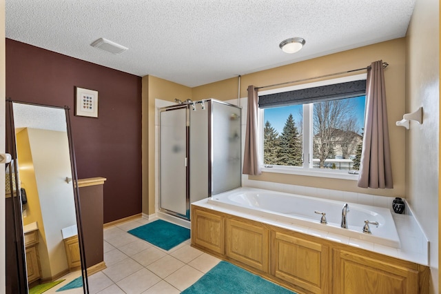 bathroom with tile patterned flooring, a garden tub, a shower stall, and a textured ceiling