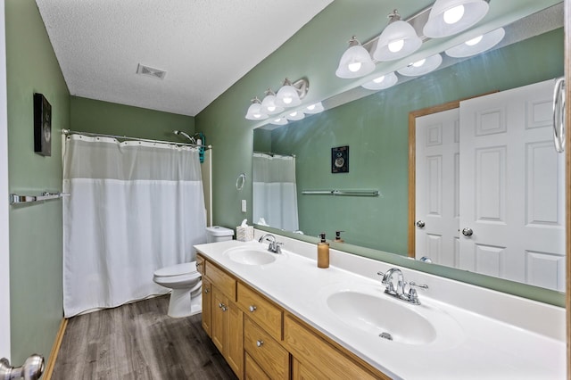 bathroom featuring a sink, a textured ceiling, toilet, and wood finished floors