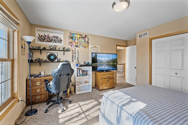 carpeted bedroom featuring a closet, visible vents, a textured ceiling, and multiple windows