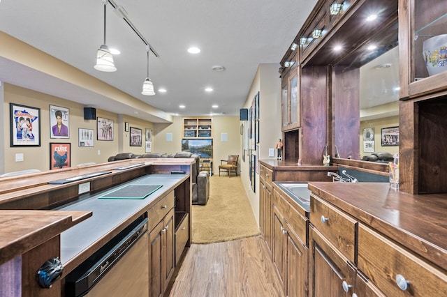 kitchen featuring dark countertops, hanging light fixtures, glass insert cabinets, a sink, and dishwashing machine