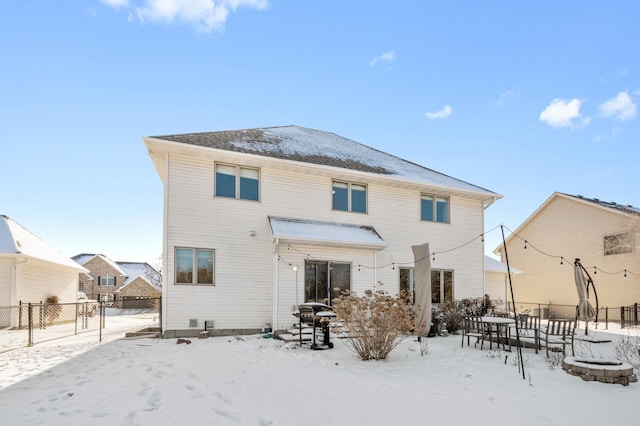 snow covered rear of property featuring fence