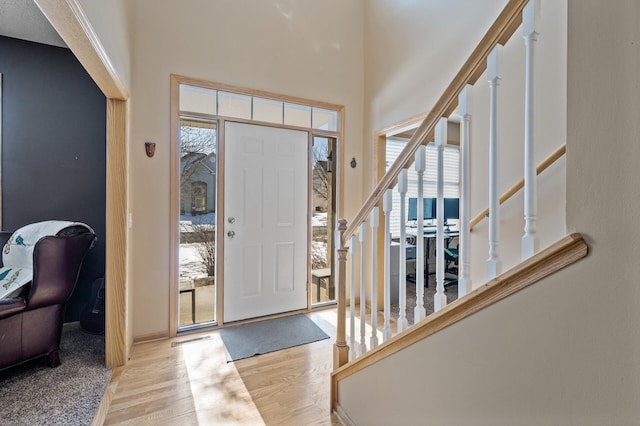 entrance foyer featuring stairs, light wood finished floors, visible vents, and a high ceiling