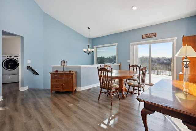 dining area featuring washer / dryer, baseboards, lofted ceiling, wood finished floors, and an inviting chandelier