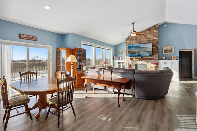 dining room with a large fireplace, ceiling fan, vaulted ceiling, and wood finished floors