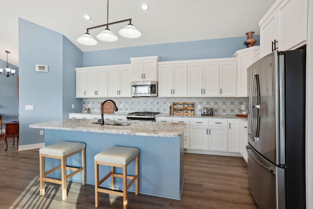 kitchen featuring white cabinets, dark wood-type flooring, a sink, stainless steel appliances, and backsplash