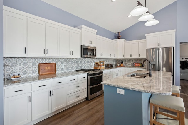 kitchen with a breakfast bar area, a sink, appliances with stainless steel finishes, decorative backsplash, and washer / clothes dryer