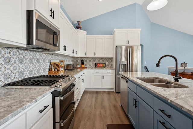 kitchen featuring white cabinetry, appliances with stainless steel finishes, vaulted ceiling, and a sink