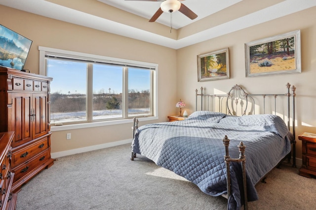 bedroom with carpet, a raised ceiling, ceiling fan, and baseboards