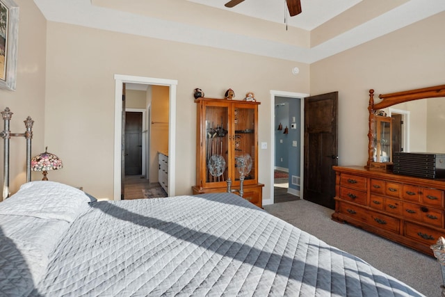 bedroom with ensuite bath, carpet flooring, a ceiling fan, and baseboards