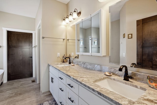 full bath with tiled shower, a sink, and double vanity