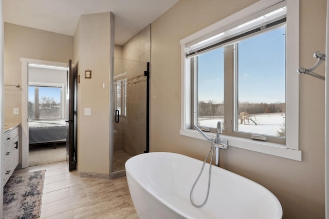 full bathroom with a stall shower, plenty of natural light, a freestanding bath, and vanity