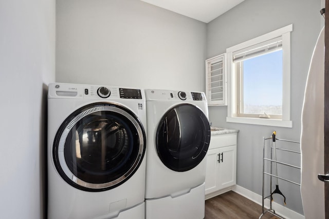 laundry area featuring separate washer and dryer, dark wood-style flooring, cabinet space, and baseboards