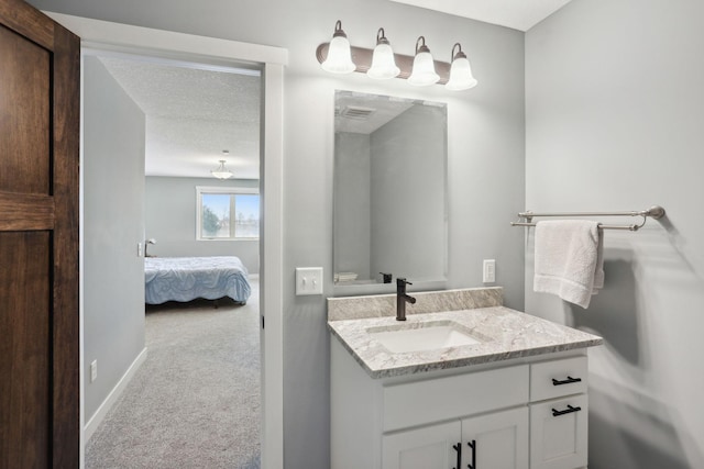 ensuite bathroom with visible vents, baseboards, connected bathroom, a textured ceiling, and vanity