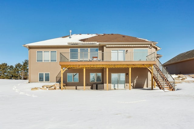 snow covered rear of property featuring a deck and stairway