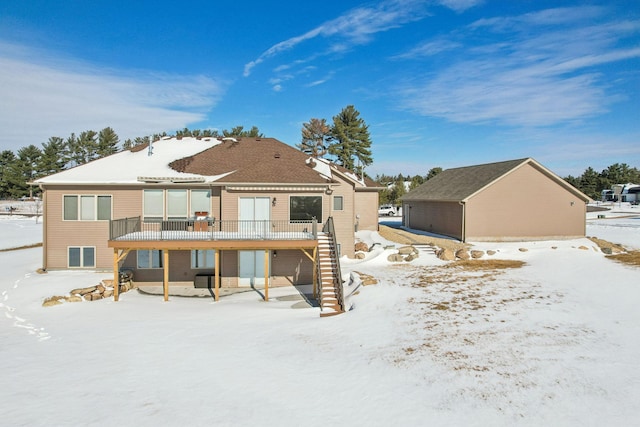 snow covered back of property with stairway and a wooden deck