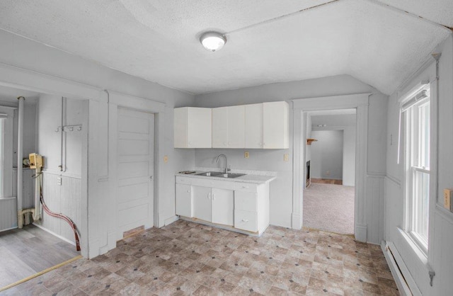 kitchen featuring light countertops, light floors, white cabinetry, a baseboard heating unit, and a sink