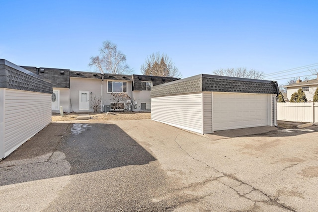 detached garage featuring fence and cooling unit