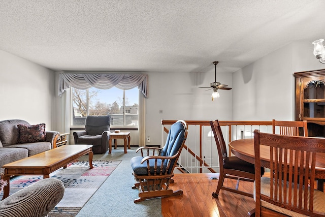 carpeted living area with ceiling fan and a textured ceiling