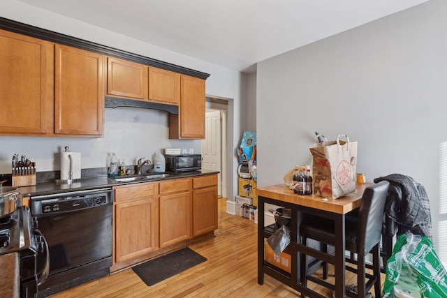 kitchen with a sink, light wood-type flooring, black appliances, brown cabinetry, and dark countertops