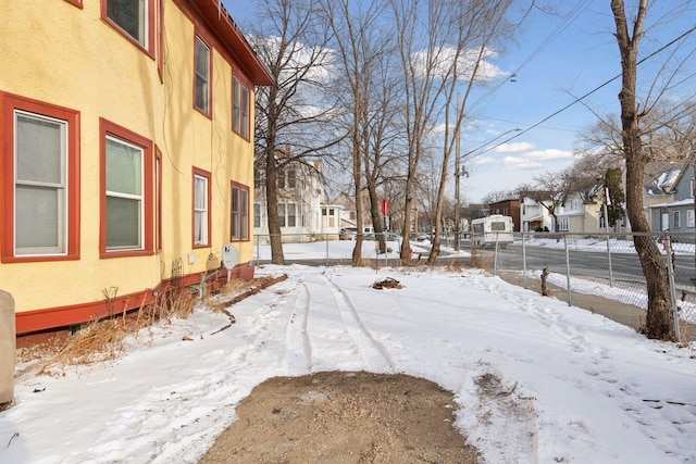 yard covered in snow featuring fence and a residential view