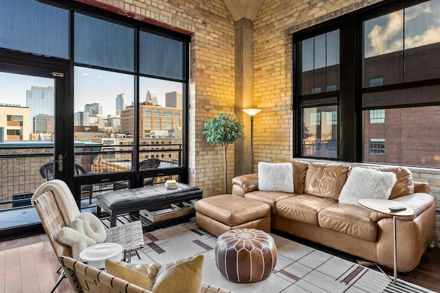 living room with brick wall, a high ceiling, a city view, and wood finished floors