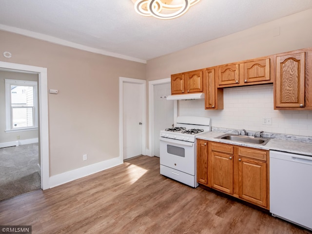 kitchen with under cabinet range hood, white appliances, a sink, light countertops, and tasteful backsplash