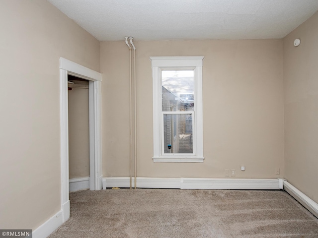 unfurnished bedroom with carpet, a baseboard heating unit, and baseboards