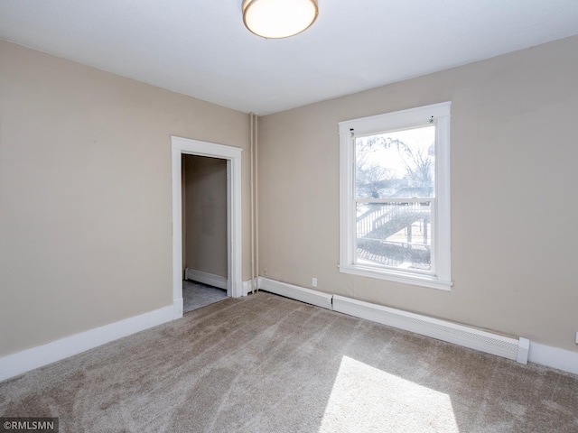 spare room featuring a baseboard heating unit, a baseboard radiator, light colored carpet, and baseboards