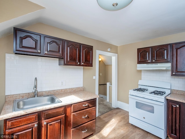 kitchen with under cabinet range hood, a sink, light wood-style floors, white range with gas cooktop, and light countertops