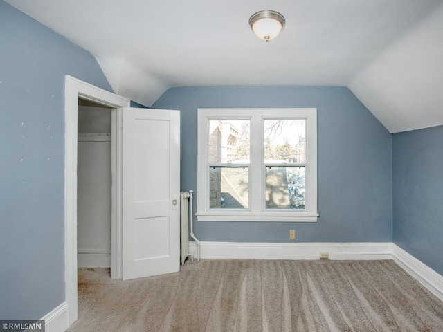 additional living space featuring light colored carpet, vaulted ceiling, and baseboards