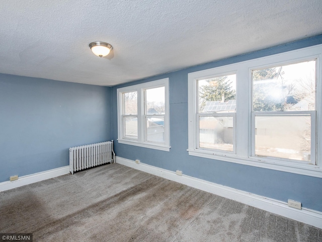 carpeted spare room featuring a healthy amount of sunlight, radiator heating unit, baseboards, and a textured ceiling