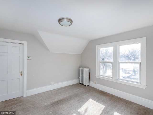 additional living space with vaulted ceiling, baseboards, light colored carpet, and radiator