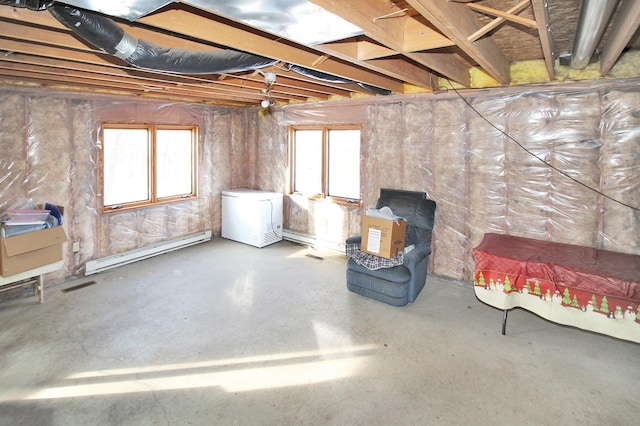 below grade area featuring a baseboard heating unit, plenty of natural light, visible vents, and refrigerator