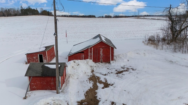 yard layered in snow featuring a barn and an outbuilding