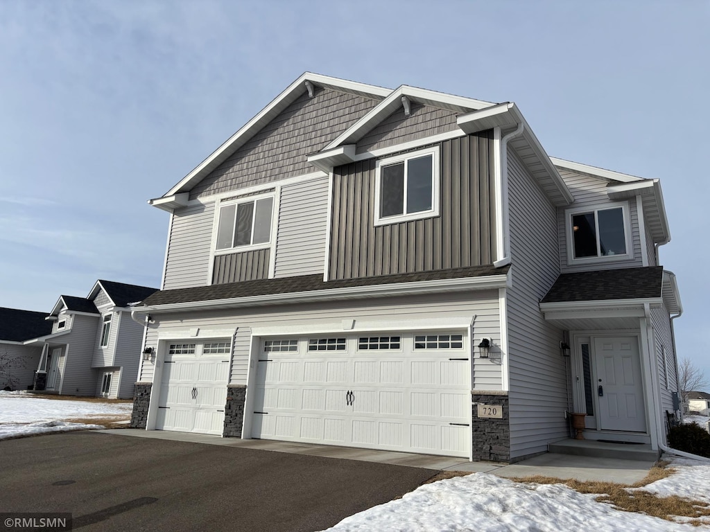 craftsman house with a garage, stone siding, driveway, and board and batten siding