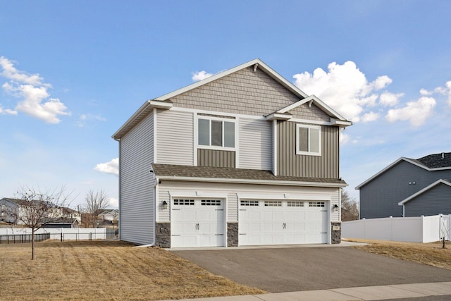 craftsman-style house with a garage, stone siding, board and batten siding, and aphalt driveway