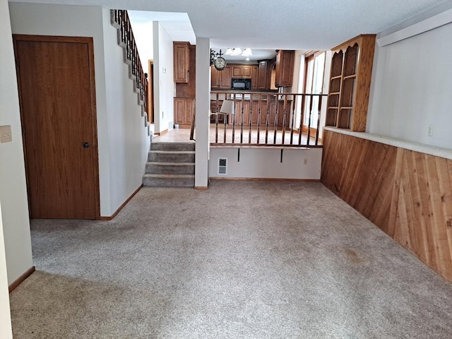 unfurnished living room with light carpet, stairway, visible vents, and baseboards