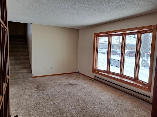 empty room featuring carpet floors, a baseboard radiator, a textured ceiling, baseboards, and stairs