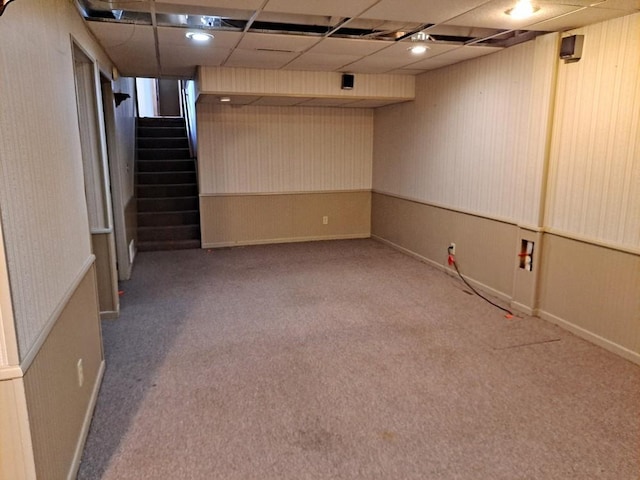 finished basement featuring stairs, a drop ceiling, and carpet flooring