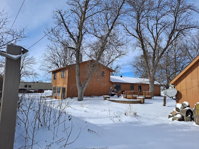 snow covered rear of property with a wooden deck