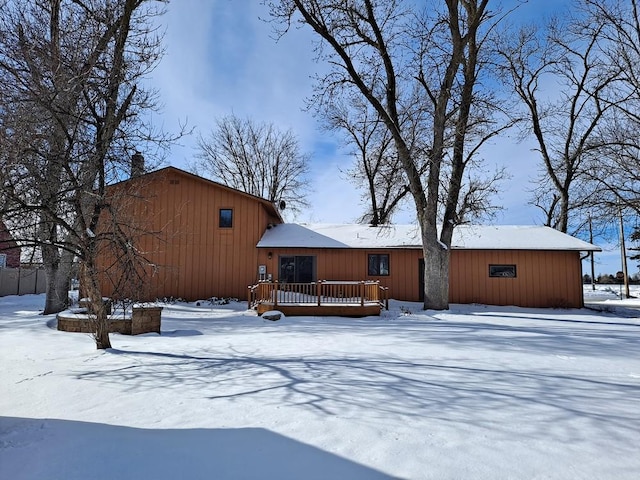 snow covered rear of property with a deck