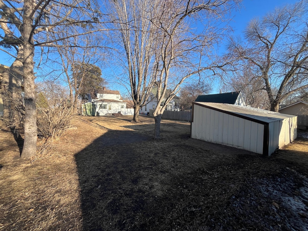 view of yard with fence, a storage unit, and an outbuilding