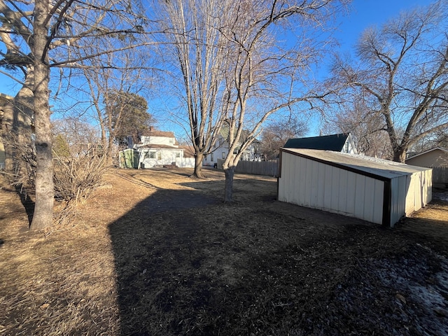 view of yard with fence, a storage unit, and an outbuilding