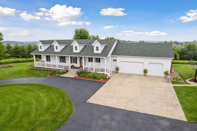 view of front of home featuring driveway, covered porch, an attached garage, and a front yard