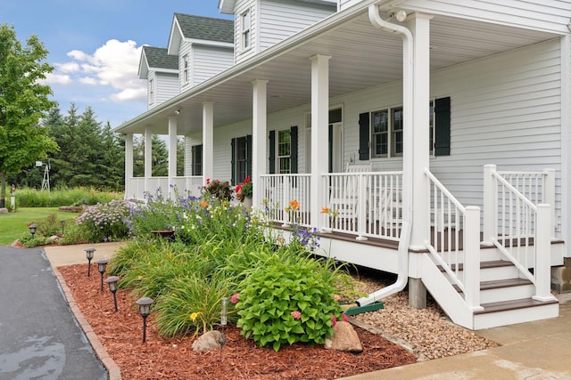 entrance to property featuring a porch and a shingled roof