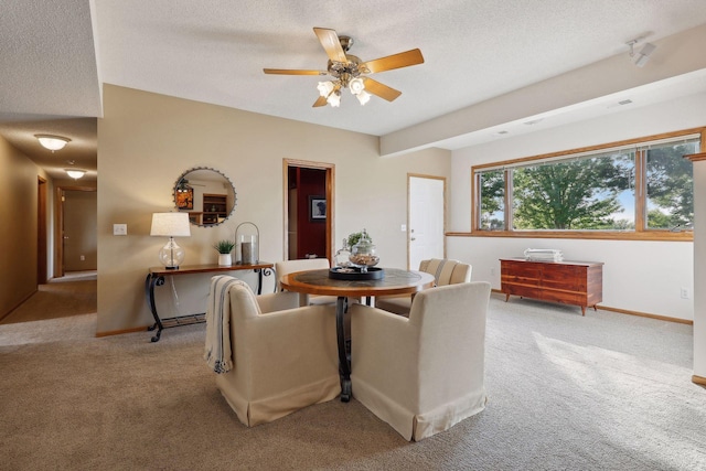 dining area featuring a textured ceiling, baseboards, and light colored carpet