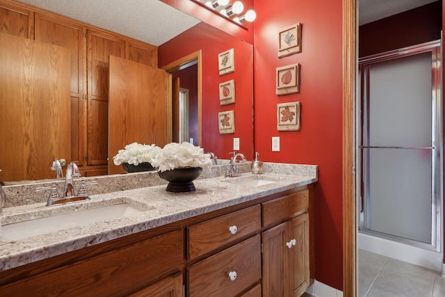 bathroom featuring double vanity, a stall shower, a sink, and tile patterned floors