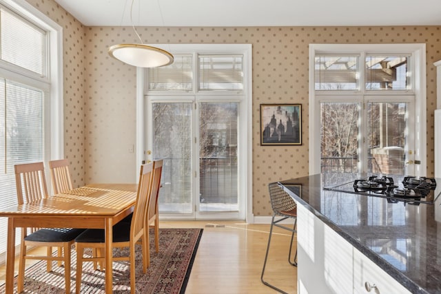 dining area with baseboards, light wood-style floors, and wallpapered walls